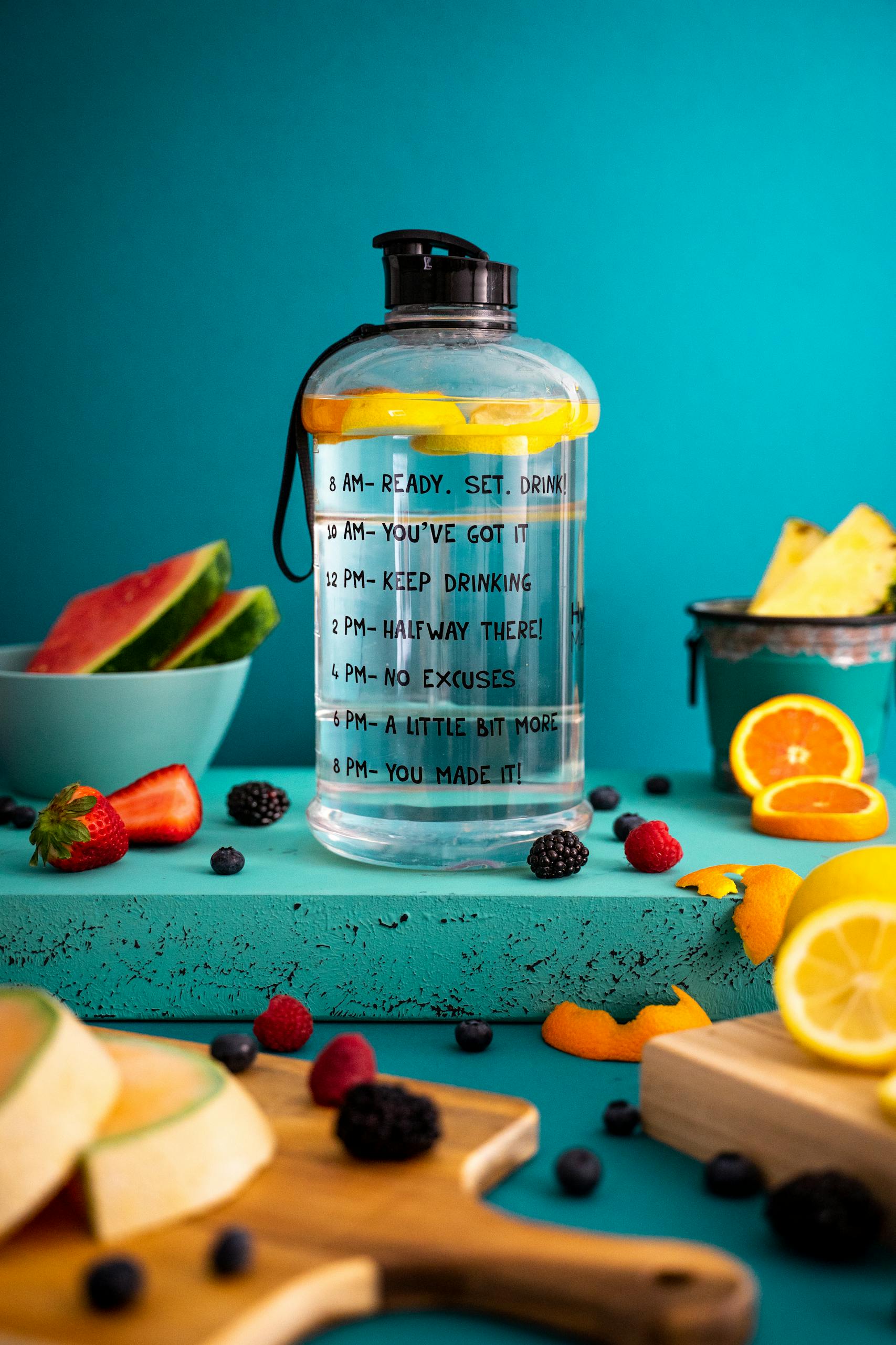 Bright composition of mixed fruits around a motivational water bottle indoors.